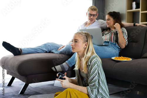 Happy young family sitting on sofa and playing video game in living room at home.