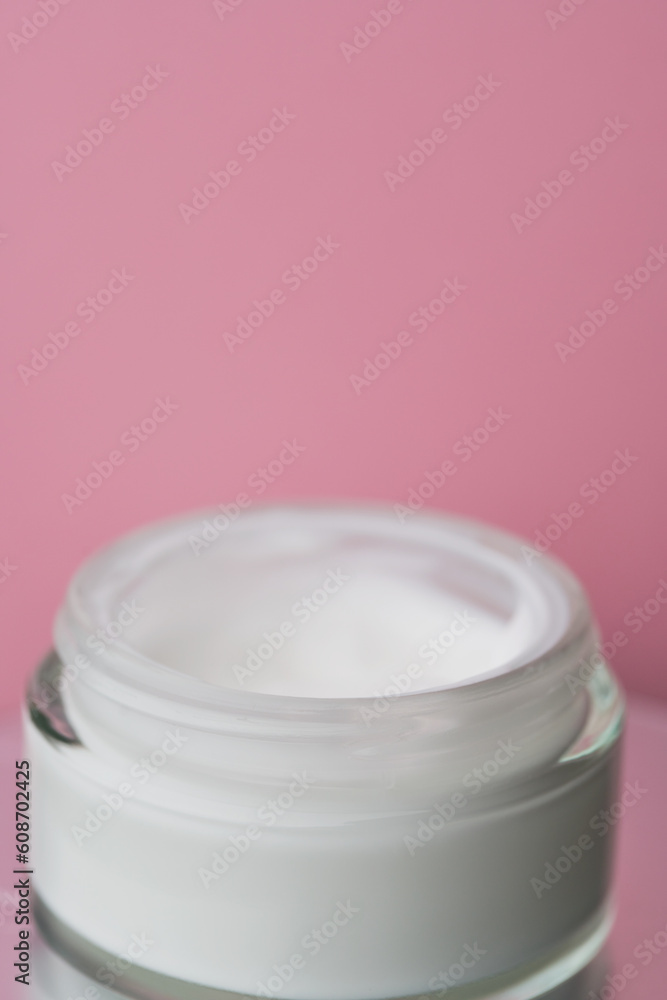 Glass jar with white face cream moisturiser on pink background. Glass jar with white face cream moisturiser on pink background.