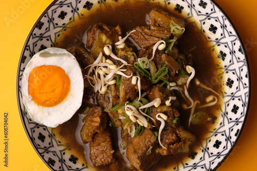 Rawon is an Indonesian beef soup. Originating from East Java, rawon utilizes the black keluak nut as the main seasoning, which gives a dark color and nutty flavor to the soup. photo
