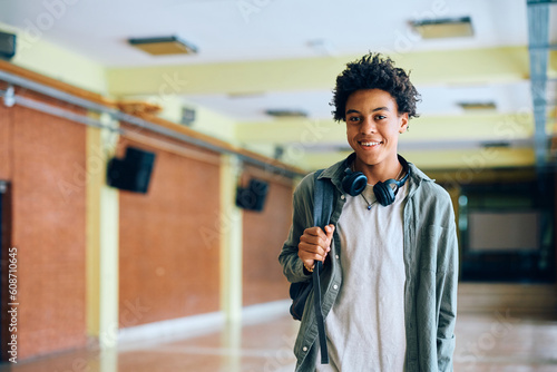 Happy black teenage boy in school hallway looking at camera.