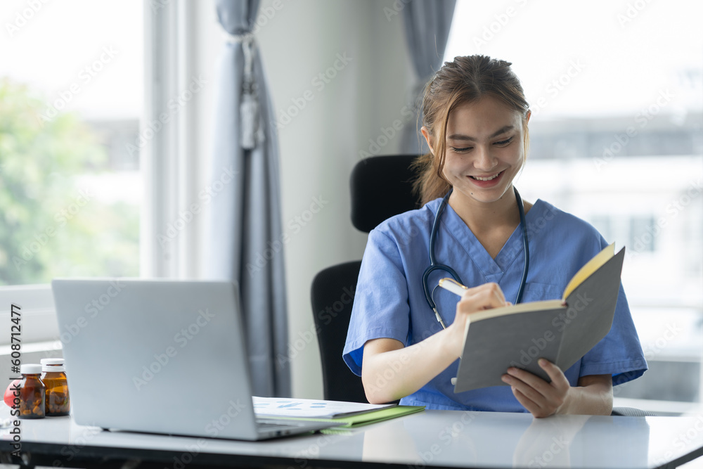 Confident female doctor, therapist sitting at desk with medical stethoscope Using a laptop and writing notes in a medical journal. planning ideas Study the treatment system, analyze life insurance. Confident female doctor, therapist sitting at desk with medical stethoscope Using a laptop and writing notes in a medical journal. planning ideas Study the treatment system, analyze life insurance.