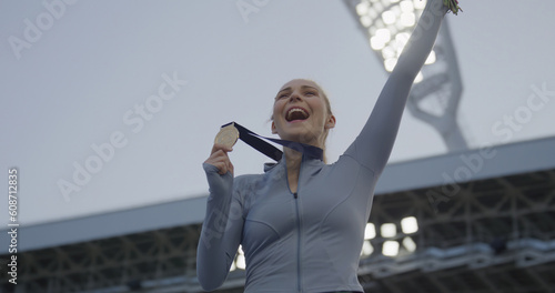 Young Female Athlete Celebrates a Win on a podium, receives a gold medal