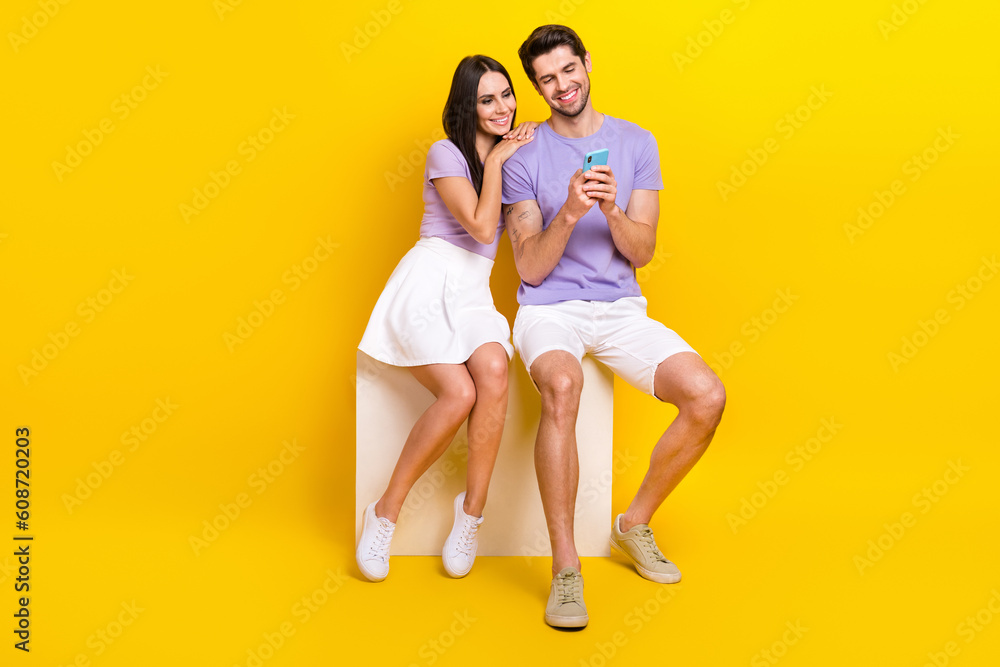 Full size photo of attractive woman man sit cube booking honeymoon tickets wear trendy purple clothes isolated on yellow color background Full size photo of attractive woman man sit cube booking honeymoon tickets wear trendy purple clothes isolated on yellow color background