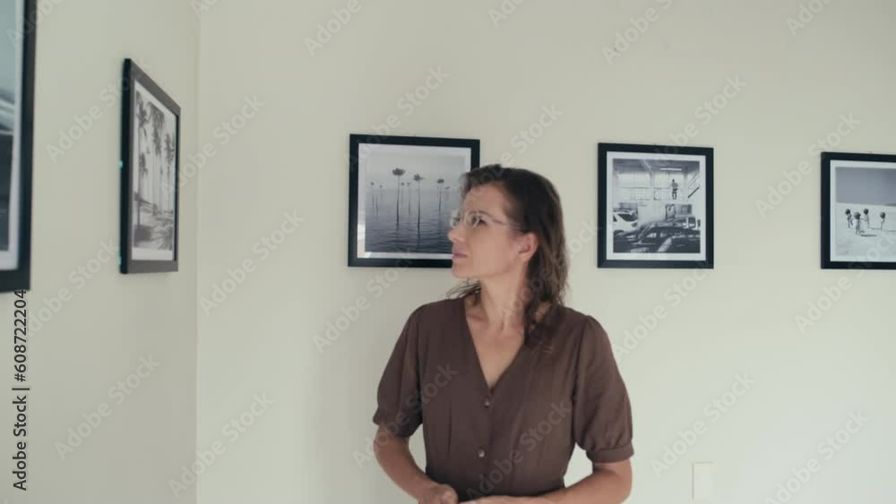 Female visitor walking along wall in art gallery and watching photo exhibition Female visitor walking along wall in art gallery and watching photo exhibition