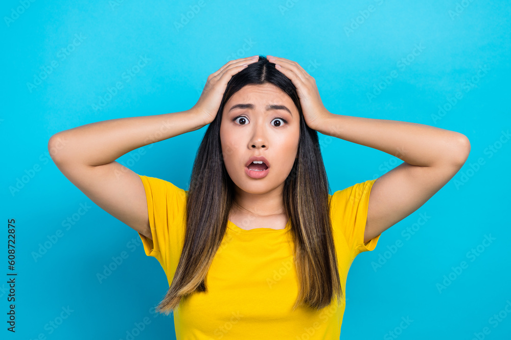 Photo of confused vietnamese lady hands head problems forgot her bank account password wear yellow t-shirt isolated on blue background Photo of confused vietnamese lady hands head problems forgot her bank account password wear yellow t-shirt isolated on blue background
