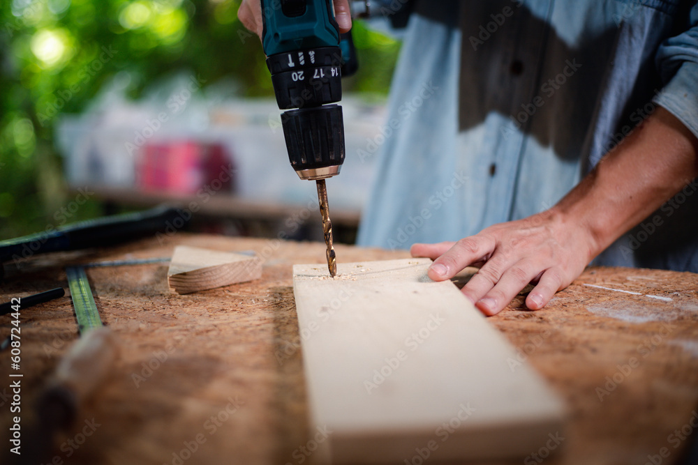 Hands of carpenter uses hand drill to assemble the wood in the wood studio at home Hands of carpenter uses hand drill to assemble the wood in the wood studio at home