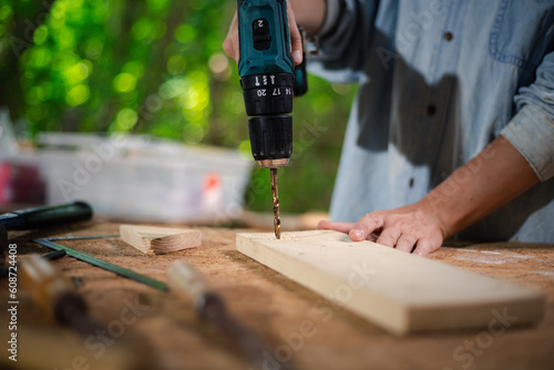 Hands of carpenter uses hand drill to assemble the wood in the wood studio at home