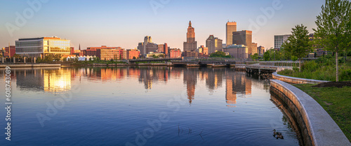 Providence downtown skyline, buildings, and curving riverbank trail at sunrise, tranquil water reflections over the River in the capital city of Rhode Island