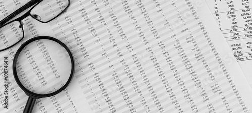 Magnifying glass and eye glasses on financial statement.