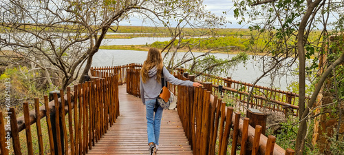 girl walking on wooden bridge in the middle of the african savannah photo