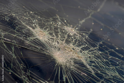 Broken windshield glass. Texture of shimmering cracks, splinters, breaks on a dark background.