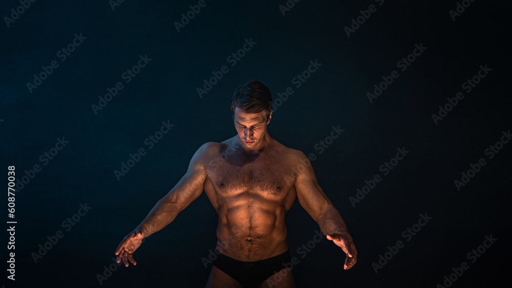 Fototapeta premium A muscular athlete in an epic pose, fog and smoke on the background, warm mystical light from below, the concept of the antique beauty of the human body