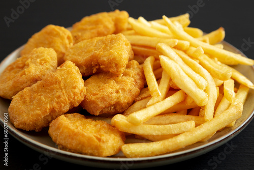 Homemade Chicken Nuggets and French Fries with Ketchup on black background, side view. Close-up.