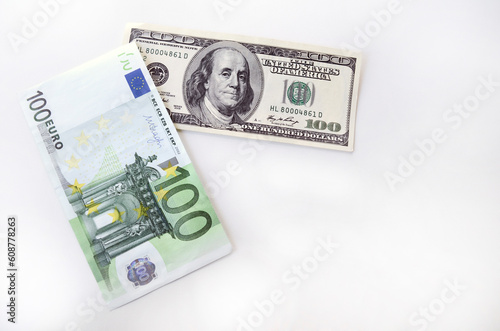 One hundred dollar bill and one hundred euros on a white background.