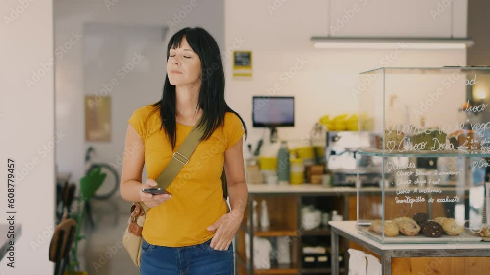 Beautiful woman walking through coffee shop with smartphone Beautiful woman walking through coffee shop with smartphone