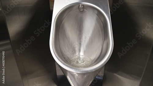 Sanitary metal urinal, toilet bowl in public bathroom with hygienic automatic water saving electronic flush. Urinal with urine sensor. Inductive flush toilet. WC photo