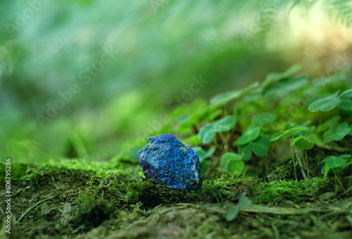 Blue mineral Chalcopyrite (Copper Pyrite) close up on natural blurred forest background. Gemstone for healing Magic Crystal Ritual, Witchcraft, spiritual esoteric practice for relax, life balance
