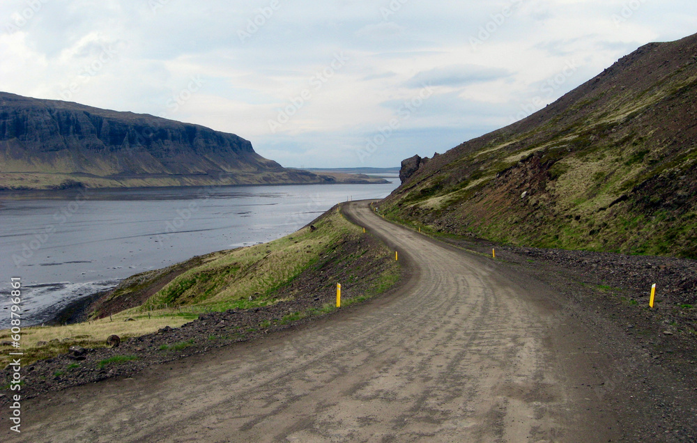A road winds alongside a mountain and river in Iceland. A road winds alongside a mountain and river in Iceland.