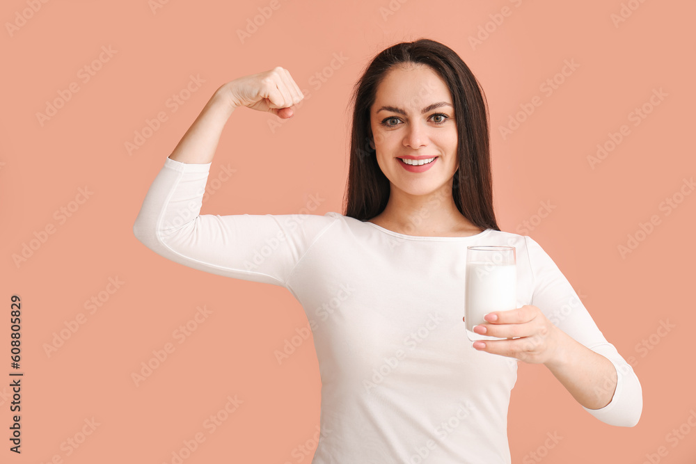 Healthy young woman with glass of milk on beige background