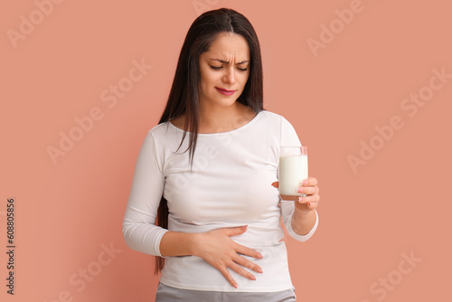Displeased young woman with lactose intolerance on beige background photo