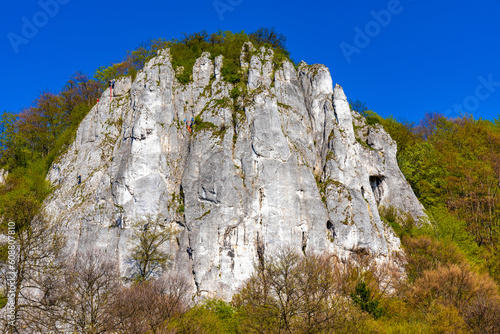 Sokolica limestone rock with free climbers in Bedkowska Valley within Jura Krakowsko-Czestochowska upland near Cracow in Lesser Poland photo