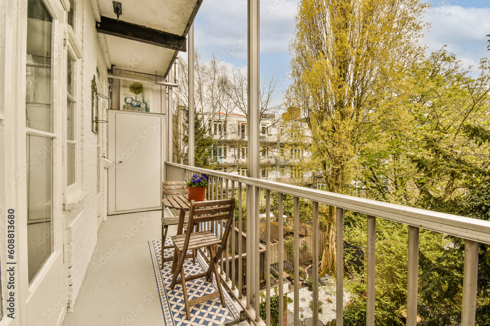 Fototapeta premium a balcony with chairs and table on the left hand side, looking out to the trees in the back yard