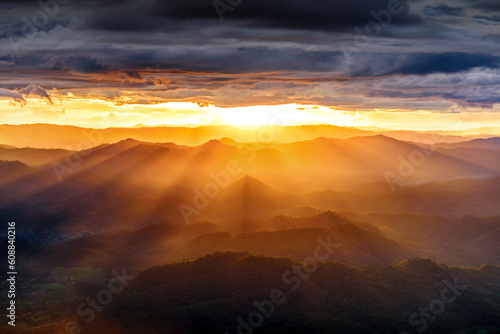 amazing dramatic cloudscape in sunset with sun rays over misty mountains landscape