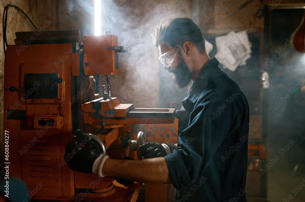 Repairman working on milling machine in smoky space of workshop Repairman working on milling machine in smoky space of workshop