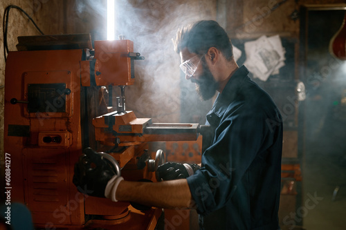 Repairman working on milling machine in smoky space of workshop