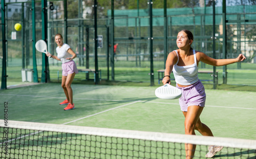 Portrait of two sports women tennis players playing padel on an outdoor court © JackF