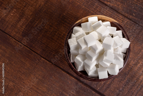 White sugar cubes in wooden bowl.