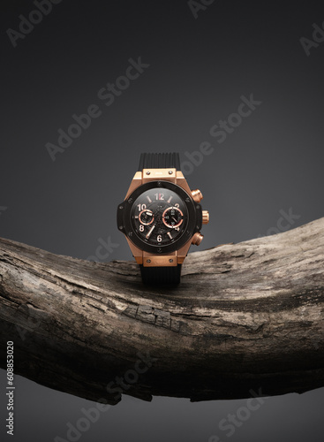 Εκτύπωση καμβά Beautiful gold men's watch with a black strap on a wooden stand, on a gray background