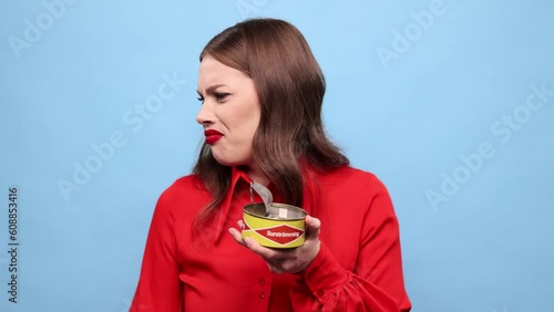 Emotional young girl eating traditional swedish dish - salted fermented herring against blue background. Concept of taste, human emotions, facial expression. Swedish cuisine photo