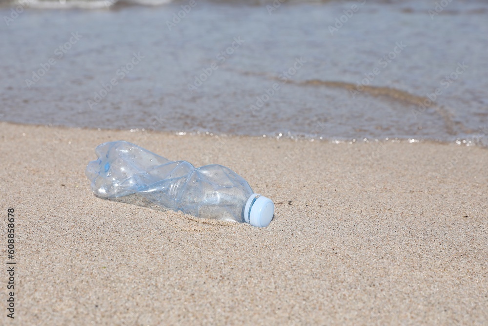 Used plastic bottle on sand near water. Recycling problem Used plastic bottle on sand near water. Recycling problem