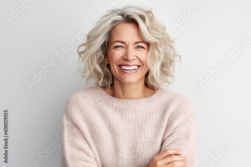 Portrait of a beautiful mature woman smiling at the camera while standing against white background
