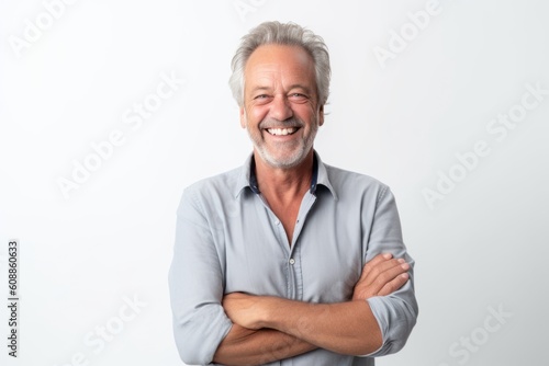 Portrait of happy senior man with crossed arms standing against white background