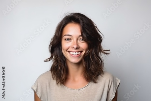 Portrait of a happy young woman looking at camera over gray background
