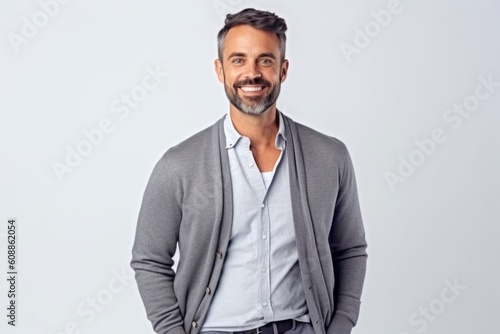 Portrait of handsome mature man smiling and looking at camera while standing against grey background