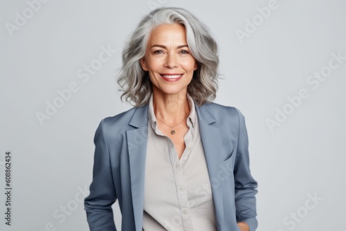 Medium shot portrait photography of a pleased woman in her 50s that is wearing a classic blazer against a white background . Generative AI