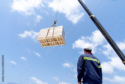A crane lifts things up high. High-risk trainee workers wear safety helmets. Start crane lifting signal. Slow rotation means that the load being lifted on the construction site is being lifted.