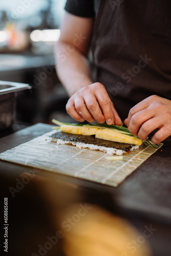 Vertical view of the hands of unknown su-chief rolling sushi and preparing sushi set in restaurant photo