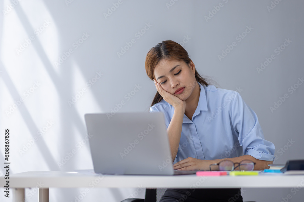 Portrait of tired young business Asian woman work with documents tax laptop computer in office. Sad, unhappy, Worried, Depression, or employee life stress concept Portrait of tired young business Asian woman work with documents tax laptop computer in office. Sad, unhappy, Worried, Depression, or employee life stress concept