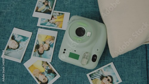Snapshots of a young couple and an instant camera lay on the teal coloured sofa