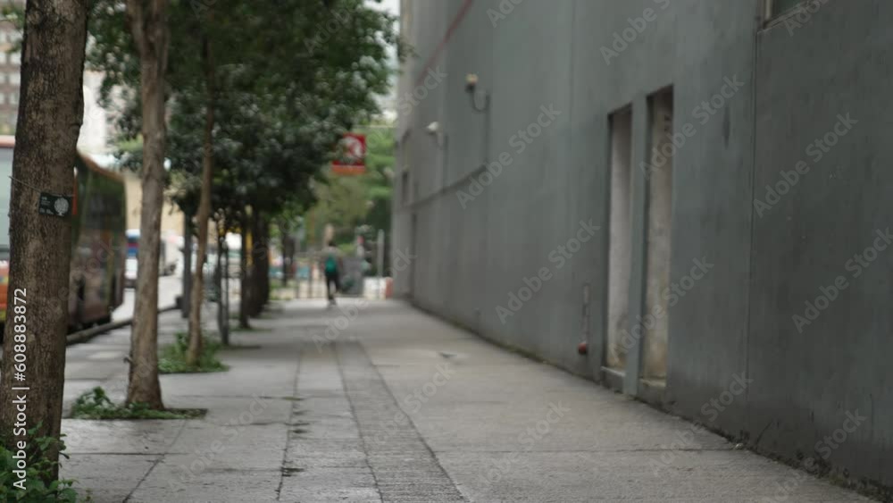 Blurred sidewalk with pedestrians in Hong Kong city, China. Focus on the city tree. Blurred sidewalk with pedestrians in Hong Kong city, China. Focus on the city tree.