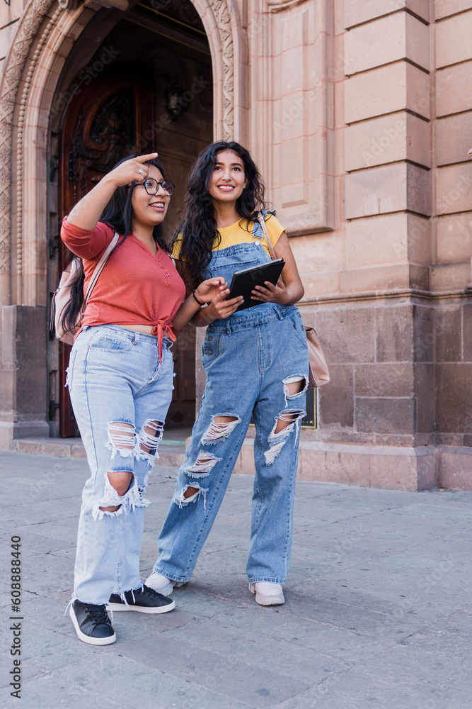 two young latin girls university students walking around city in Mexico Latin America, hispanic girls having fun in the street