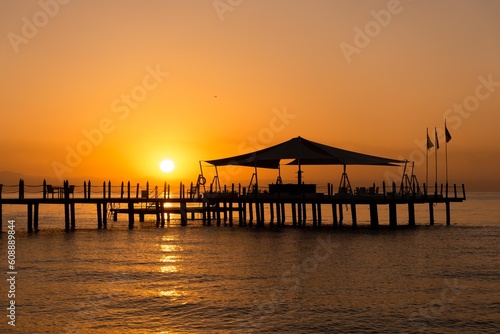 Pier at dawn. Wooden pier on the azure sea at dawn in orange tones  wallpaper  seasonal background. Orange dawn on the sea  Beldibi  Antalya  T  rkiye.