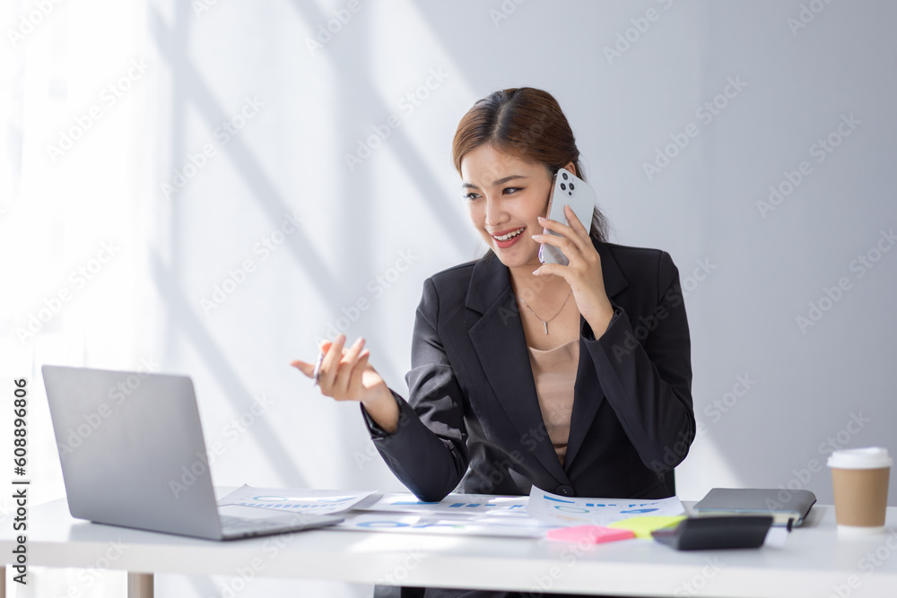 Cheerful business Asian student woman freelancer making telephone call share good news about project working in office workplace, business finance concept. Cheerful business Asian student woman freelancer making telephone call share good news about project working in office workplace, business finance concept.