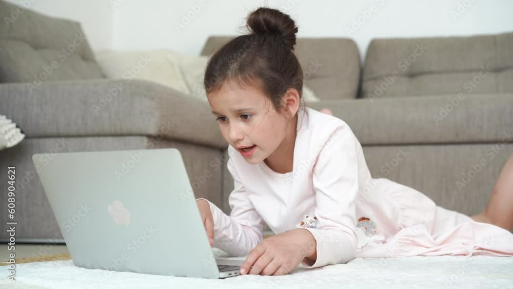 8 years child girl using laptop. Child typing on the keyboard lying on floor in living room. High quality 4k footage 8 years child girl using laptop. Child typing on the keyboard lying on floor in living room. High quality 4k footage