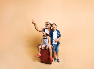 Young Indian father with his kids trolley luggage bag  summer holidays and vacations concept against beige background,  Tours and travel, copy space.