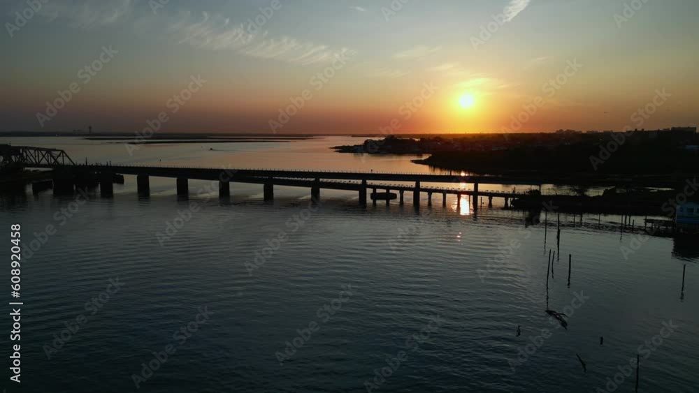 An aerial view of Jamaica Bay, while facing a golden sunrise. A train bridge is view and the water is calm. The drone camera truck left out over the water. An aerial view of Jamaica Bay, while facing a golden sunrise. A train bridge is view and the water is calm. The drone camera truck left out over the water.